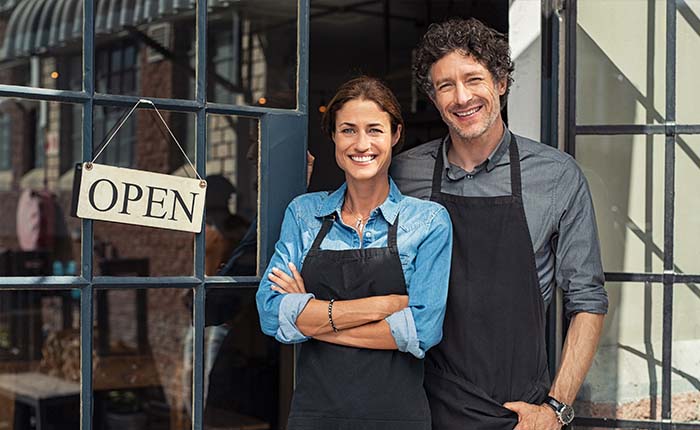 Couple standing in front of their small business needing coaching and advise